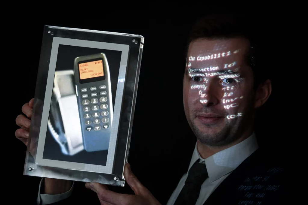 Man holding the first SMS sold as NFT at an auction.